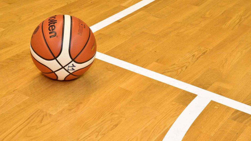 Basketball on sports floor court with white markings.