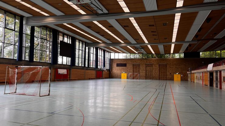 Indoor sports hall with multi-purpose flooring and goalposts for various games.