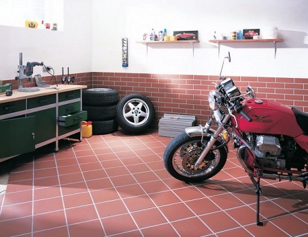 Garage with red tile flooring and a parked motorcycle