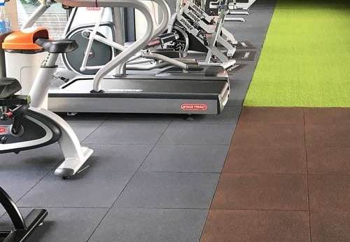 Gym with treadmills on rubber tiles and green turf strip