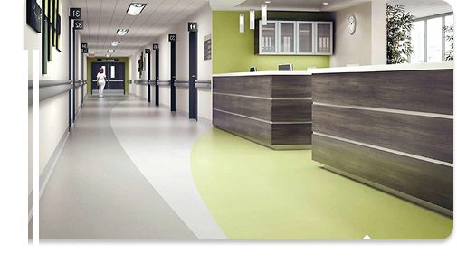 Modern hospital hallway with green and grey flooring near reception desk